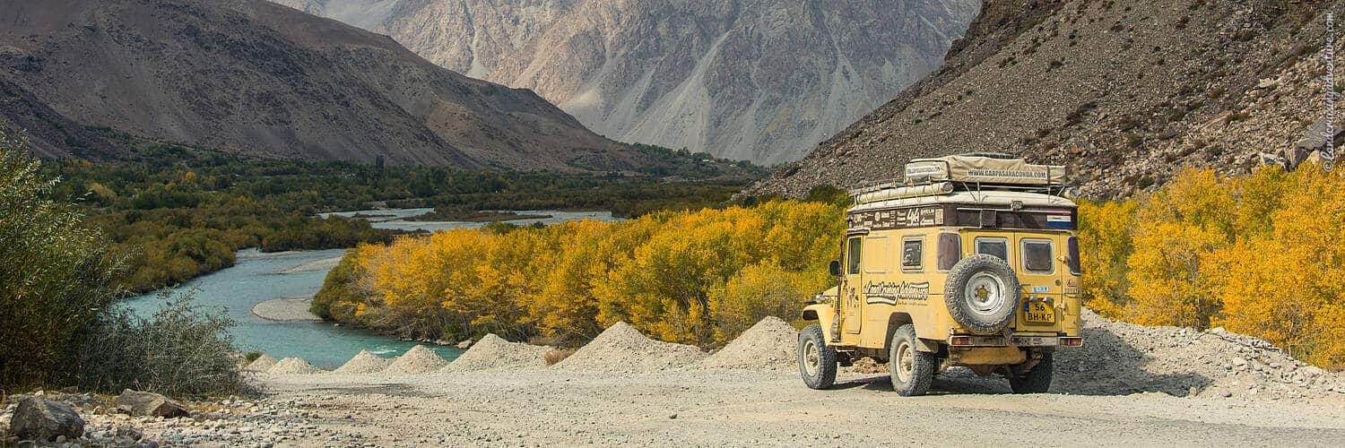 Overland Travel on the Pamir Highway in Tajikistan, mountains, autumn leaves, yellow Land Cruiser